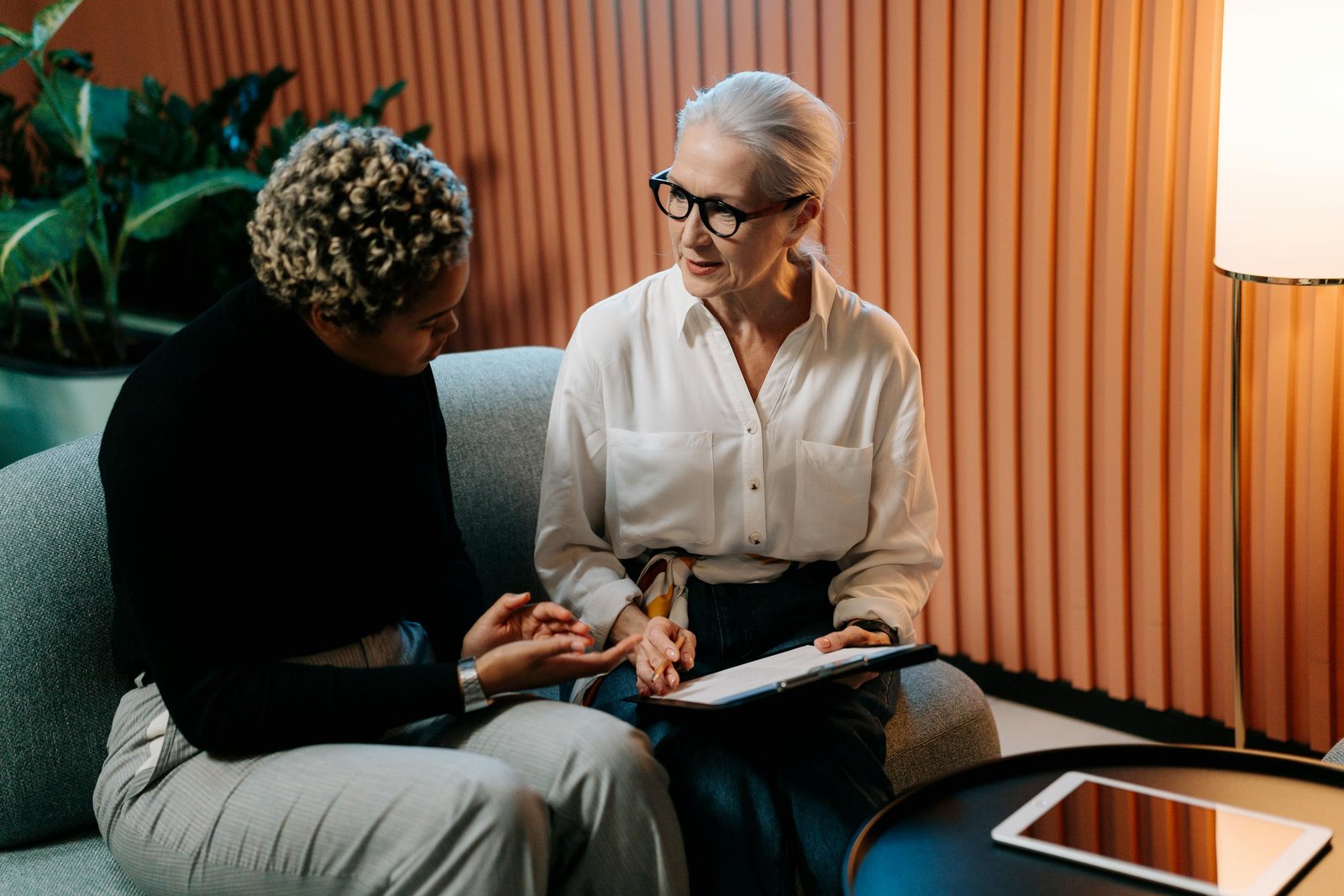 Two professional women engaged in a business discussion indoors with documents / layoffs